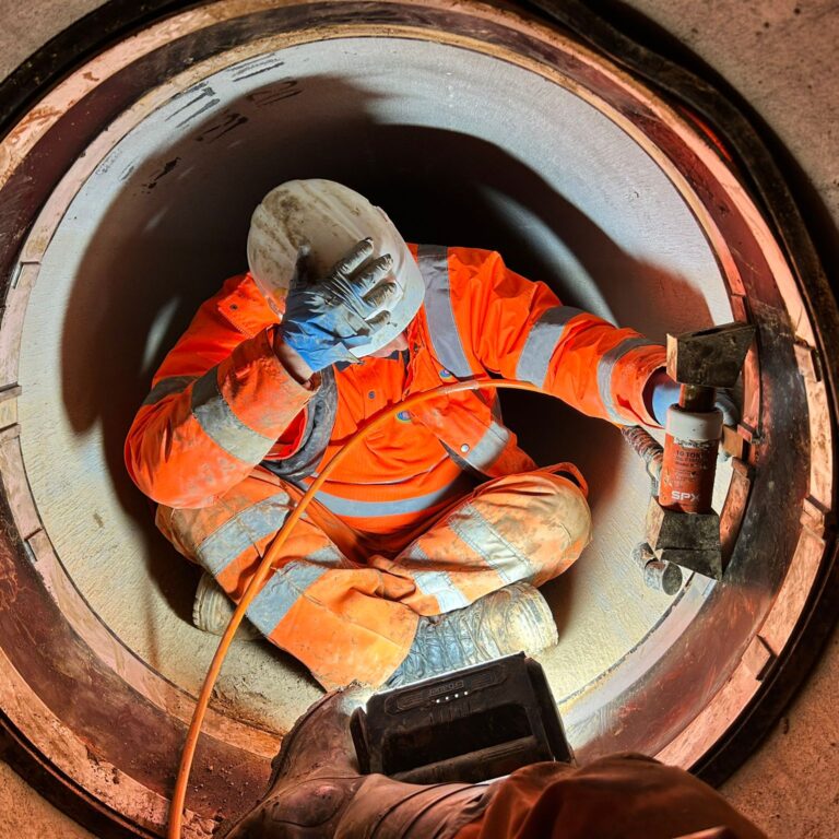man in hi-viz PPE sitting in large pipe